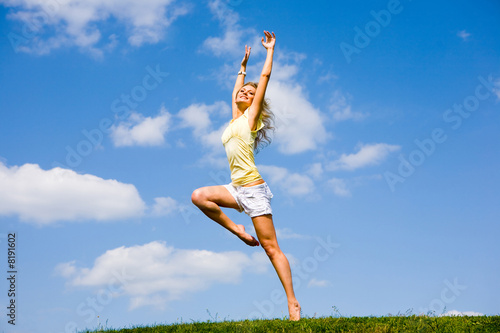 Happy young woman is dancing in a field