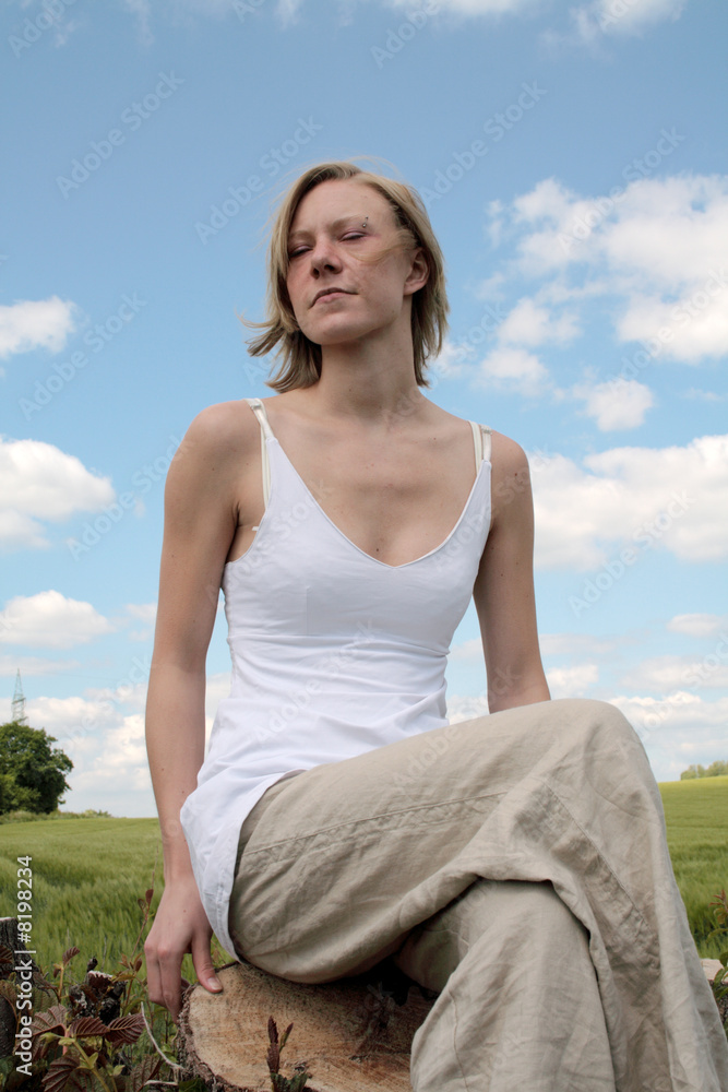 junge Frau sitzt auf einem Baumstamm