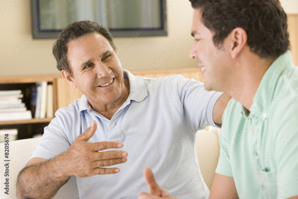 Two men in living room talking and smiling Two men in living room talking and smiling