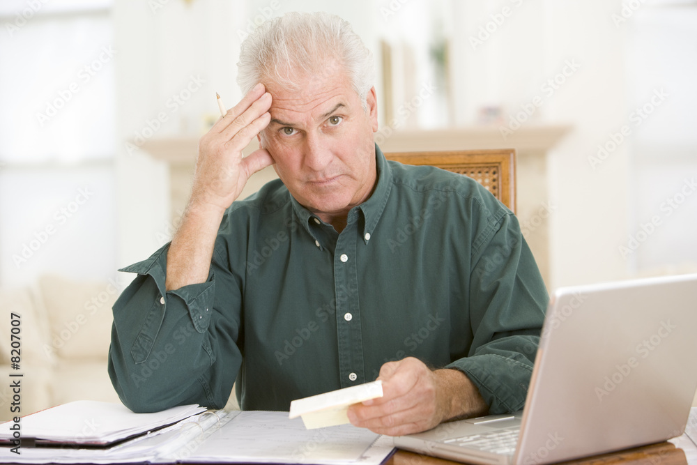 Man with laptop and paperwork looking frustrated Man with laptop and paperwork looking frustrated