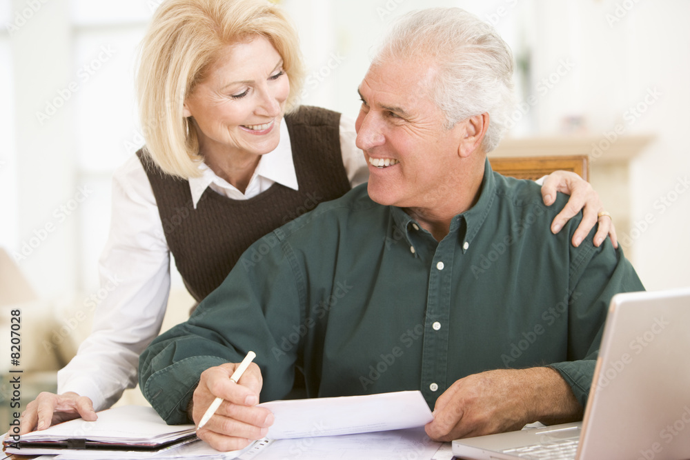 Couple with laptop and paperwork smiling Couple with laptop and paperwork smiling