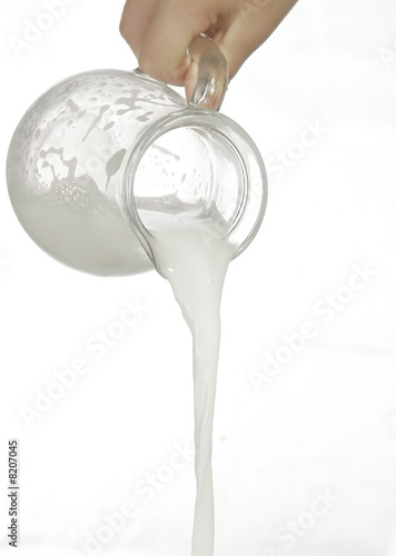 pouring milk in a glass isolated against white background