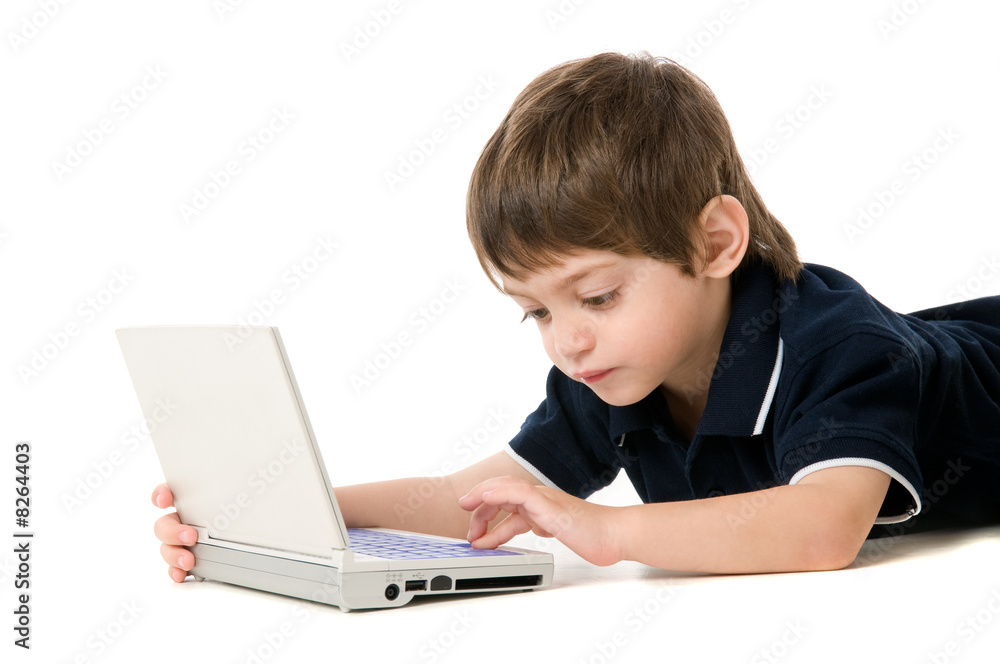 Child playing with the laptop lying on the floor Child playing with the laptop lying on the floor