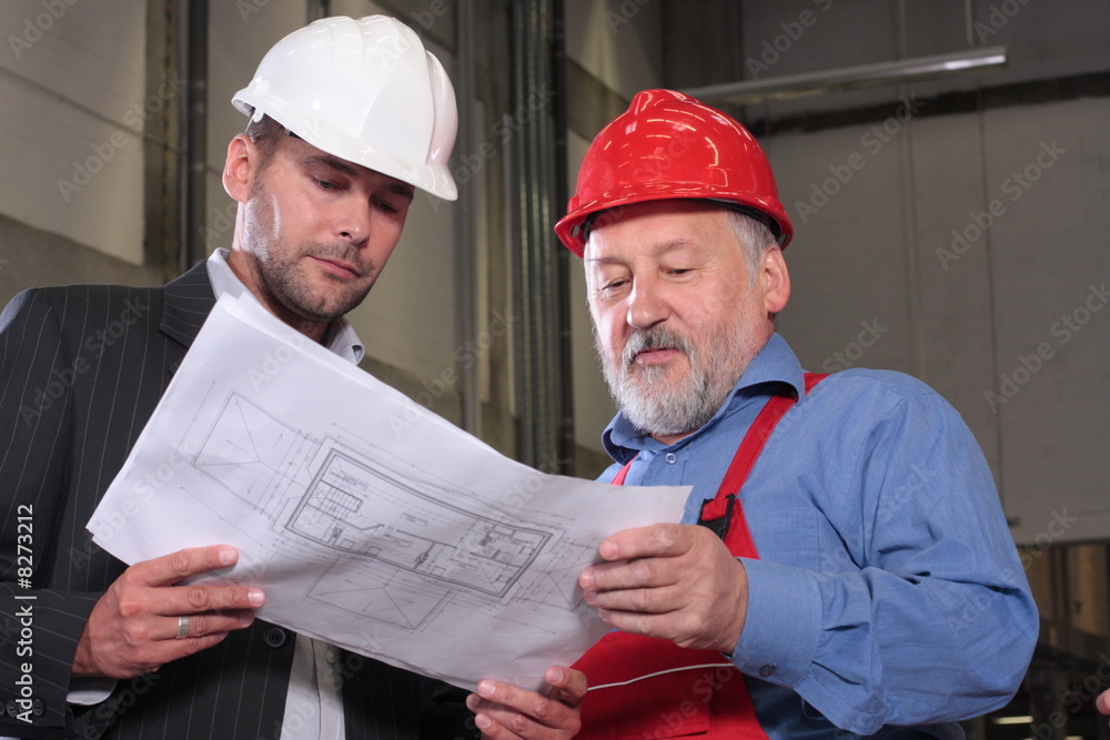 supervisor and older worker over blueprints