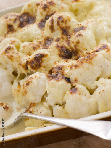 Dish of Cauliflower Cheese with serving spoon