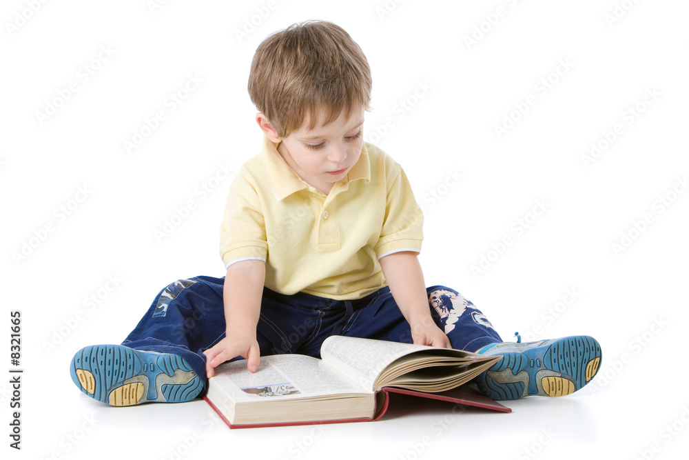 Young boy sitting on the floor reading a book Young boy sitting on the floor reading a book