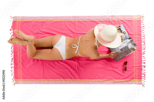 Beautiful girl tanning lying on the beach towel.
