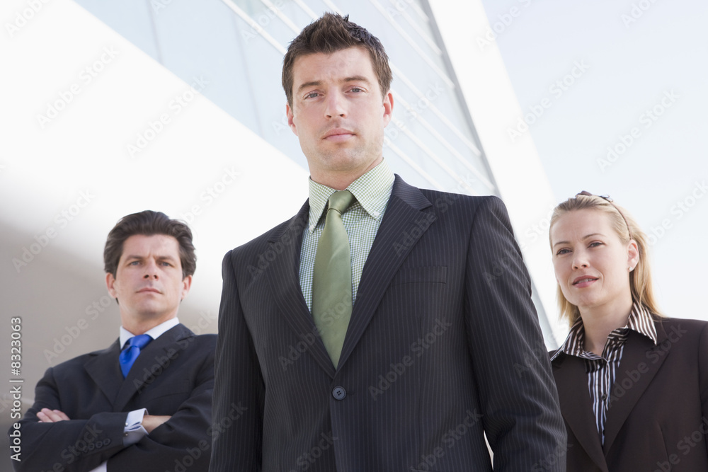 Three businesspeople standing outdoors by building Three businesspeople standing outdoors by building