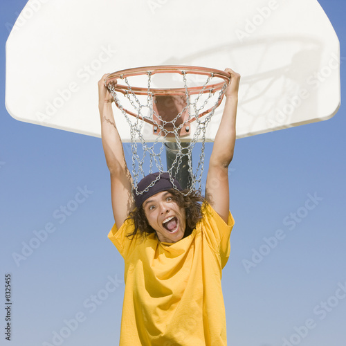 Boy hangs from basketball hoop