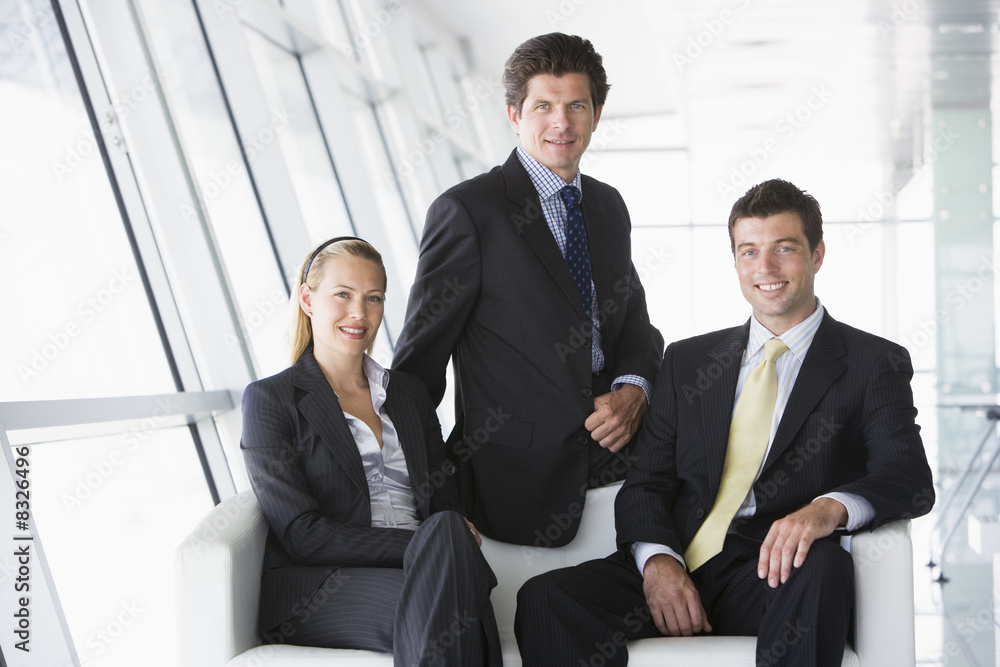 Three businesspeople sitting in office lobby smiling Three businesspeople sitting in office lobby smiling