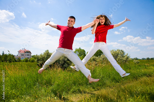 Happy Young Couple - team is jumping in the sky