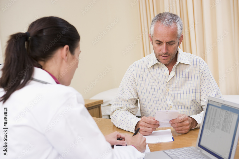 Doctor with laptop and man in doctor's office