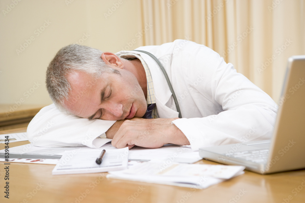 Doctor with laptop sleeping in doctor's office Doctor with laptop sleeping in doctor's office