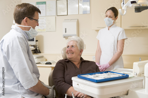 Dentist and assistant in exam room with woman