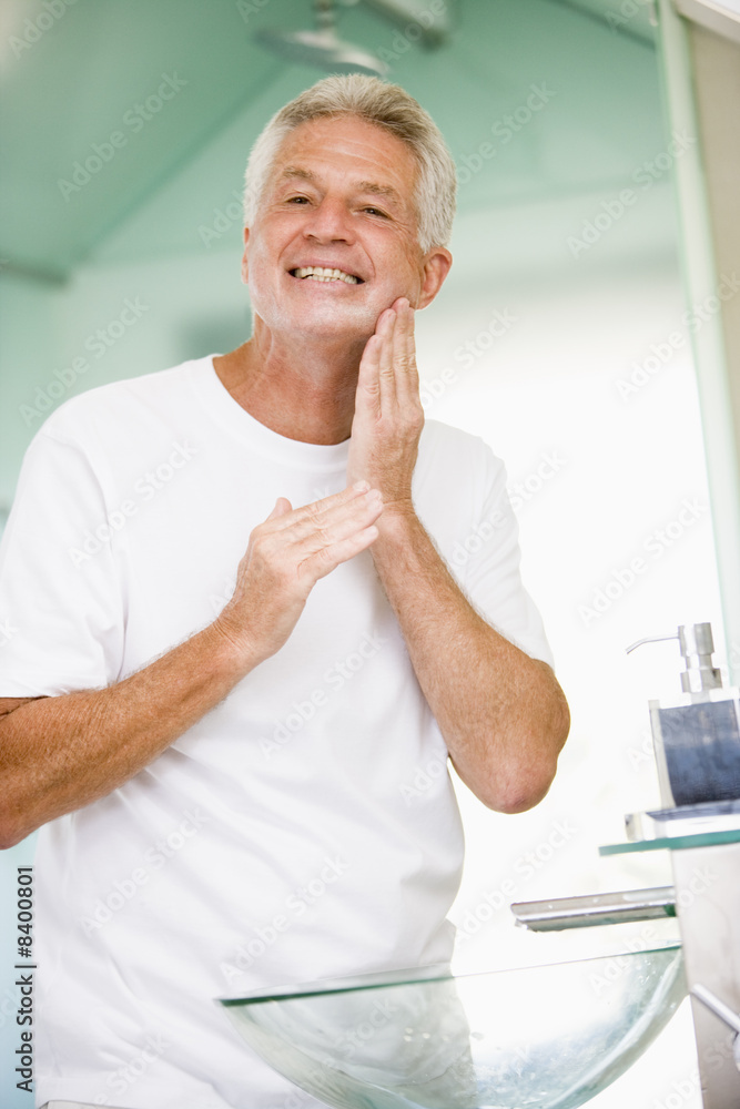 Man in bathroom applying aftershave