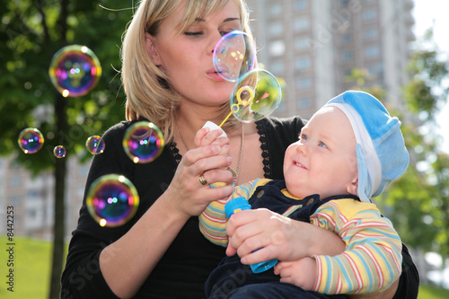 Mother with child is started up with soap bubbles