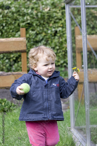 Enfant avec fleur dans un jardin près d'une serre