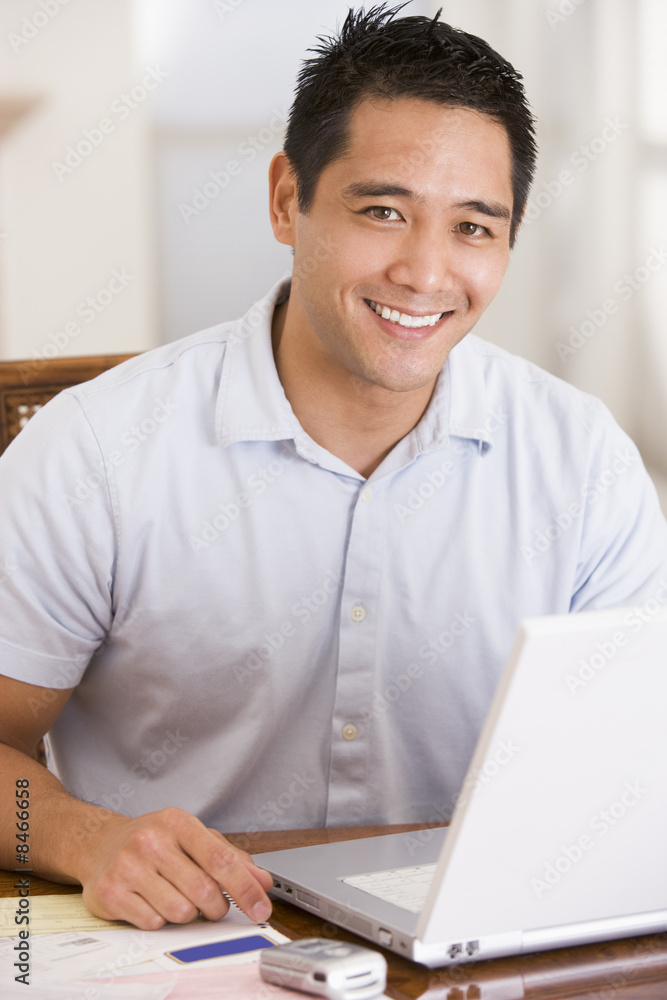 Man in dining room using laptop smiling Man in dining room using laptop smiling