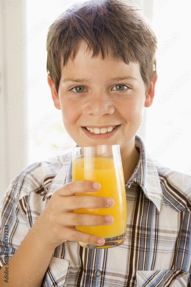 Young boy indoors drinking orange juice smiling Young boy indoors drinking orange juice smiling