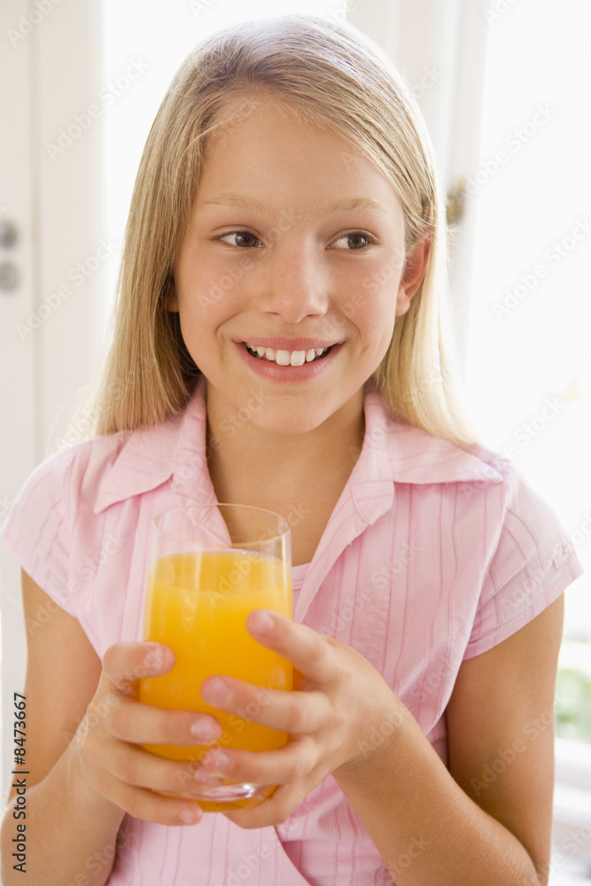 Young girl indoors drinking orange juice smiling Young girl indoors drinking orange juice smiling