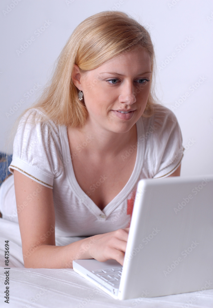 Junge Frau liegt mit Laptop auf dem Bett Junge Frau liegt mit Laptop auf dem Bett