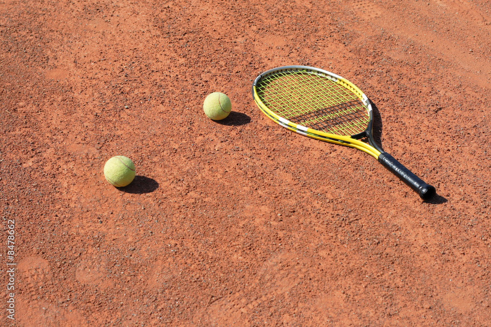 tennis-racket with two balls laying on the court