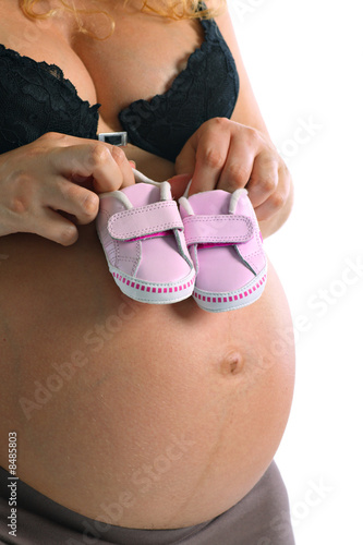 Pregnant woman with little baby shoes on her belly photo