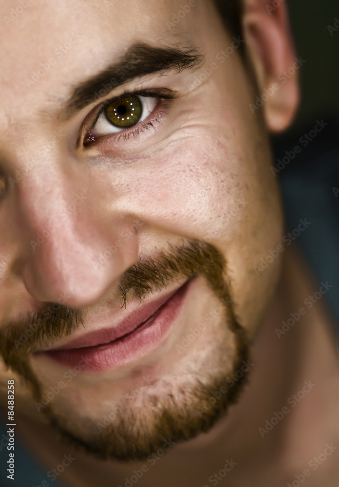 Obraz premium close-up portrait of a Caucasian man with beard, looking into the camera and smile. safe and calm expression, reflections of circular lights in the eyes.