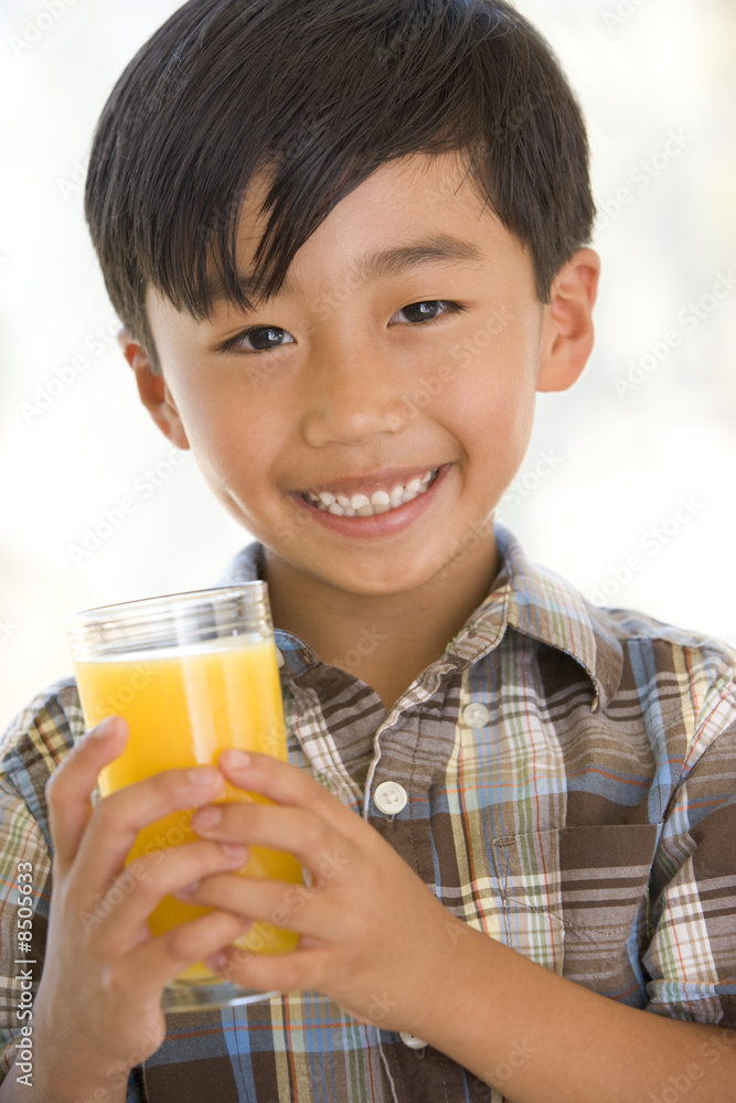Young boy indoors drinking orange juice smiling Young boy indoors drinking orange juice smiling