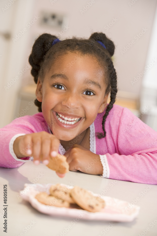 Young girl in kitchen eating cookies smiling Young girl in kitchen eating cookies smiling