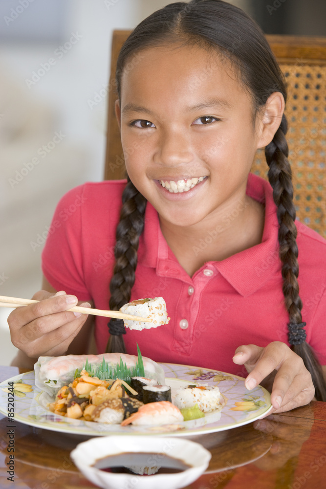 Young girl in dining room eating Chinese food smiling Young girl in dining room eating Chinese food smiling