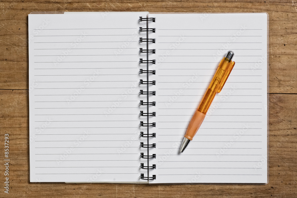Open spiral notebook with pen on wooden table. Open spiral notebook with pen on wooden table.
