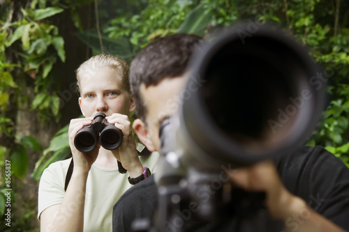 Canvastavla Pretty Woman with Binoculars and Man with Telescope in Jungle