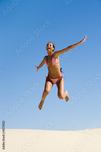 Portrait of joyful girl leaping on sandy beach