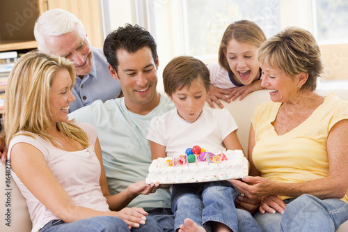 Family in living room smiling with young boy blowing out candles