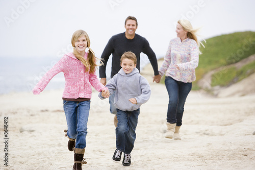 Family running at beach holding hands smiling