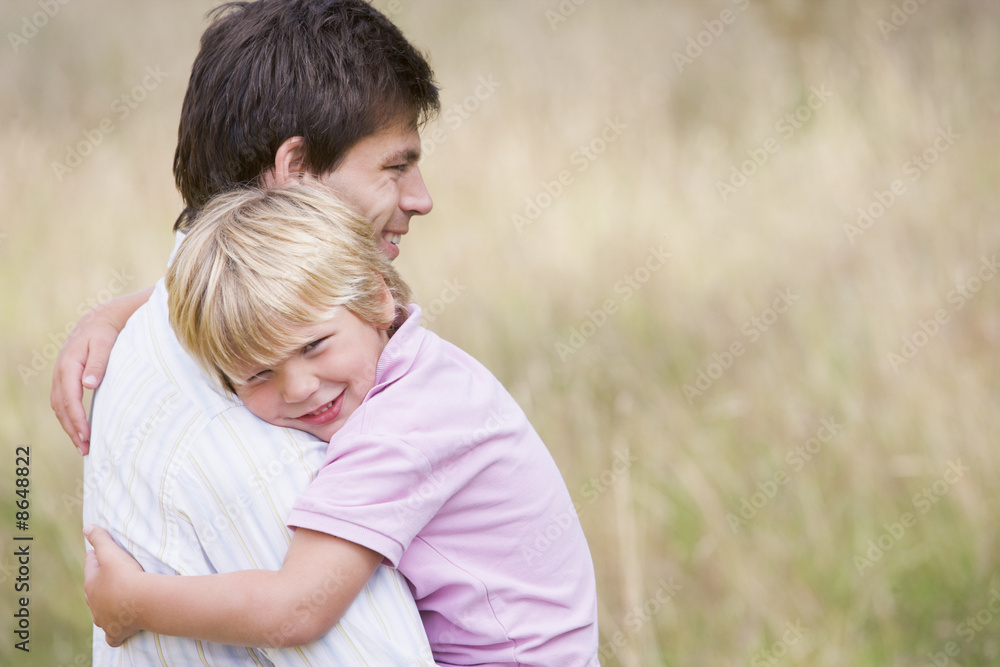 Father holding son outdoors smiling Father holding son outdoors smiling