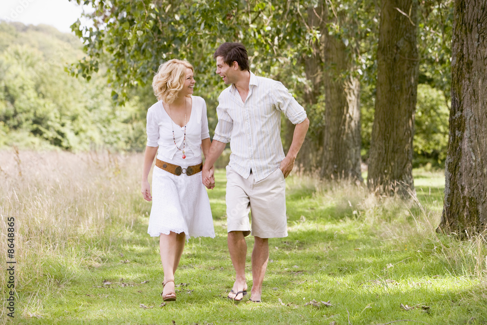 Couple walking on path holding hands smiling Couple walking on path holding hands smiling