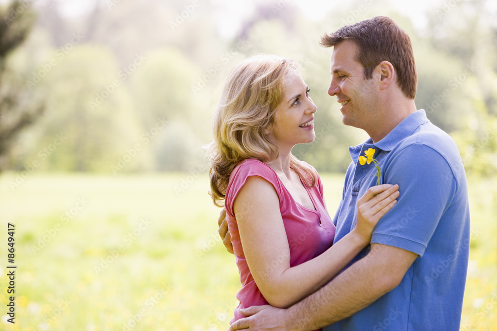 Couple embracing outdoors holding flower smiling Couple embracing outdoors holding flower smiling