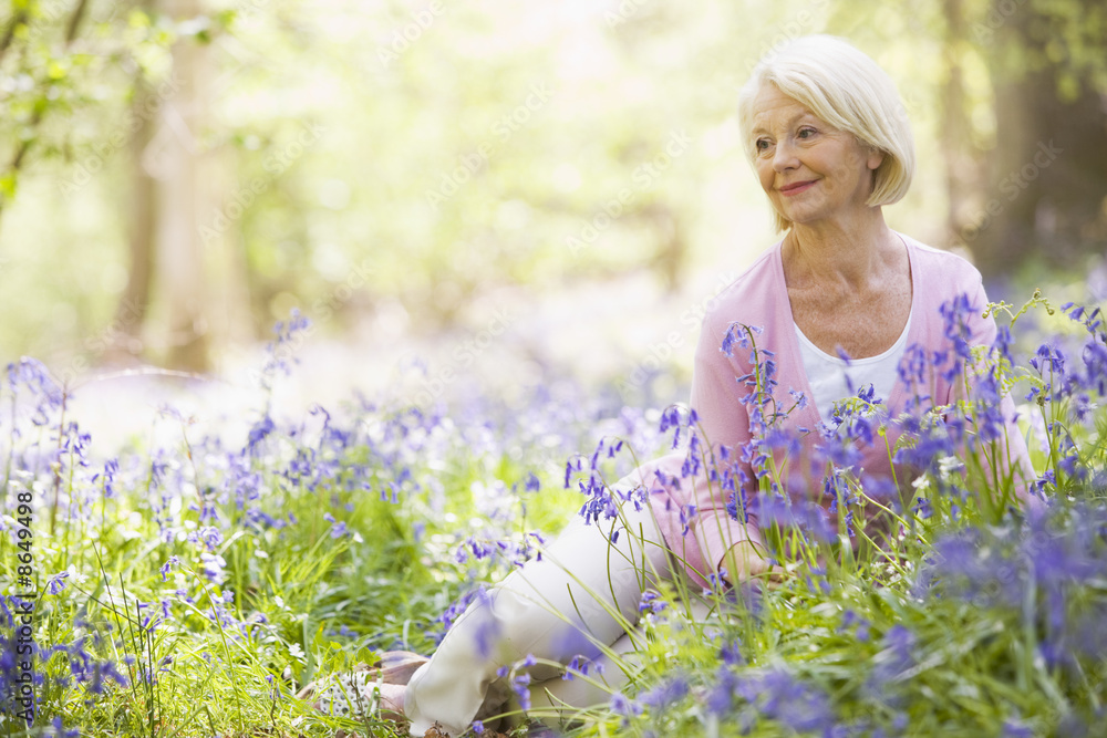 Woman sitting outdoors with flowers smiling Woman sitting outdoors with flowers smiling