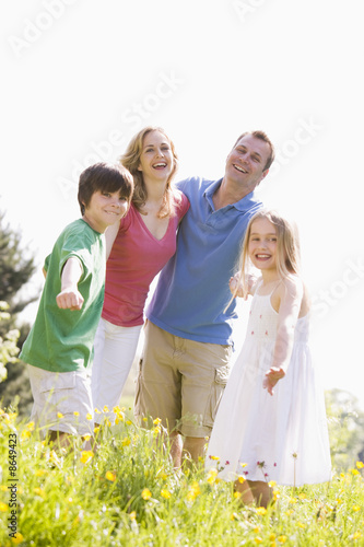 Family standing outdoors holding hands smiling