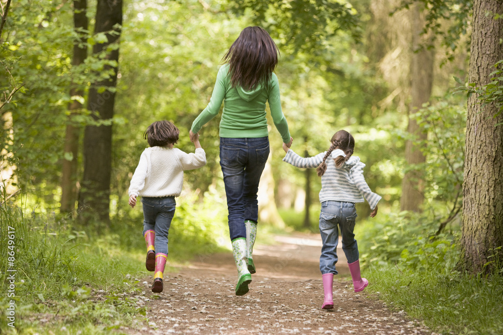 Mother and daughters skipping on path smiling Mother and daughters skipping on path smiling