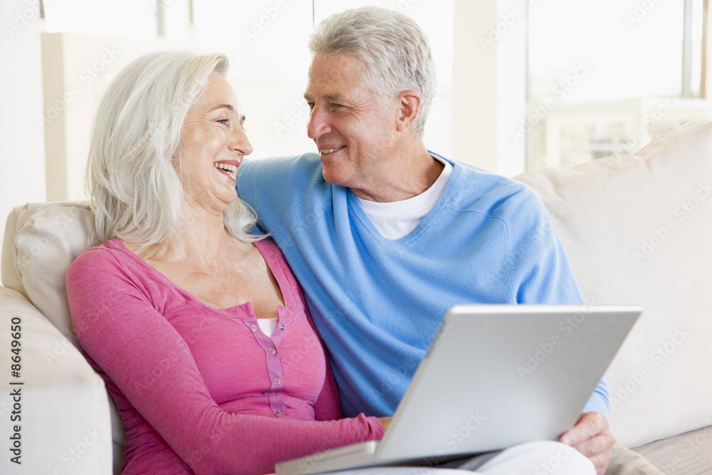 Couple in living room with laptop smiling