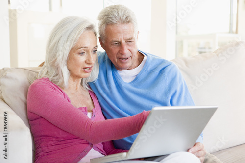 Couple in living room with laptop smiling © Monkey Business