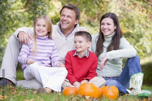 Family sitting on grass with pumpkins smiling © Monkey Business