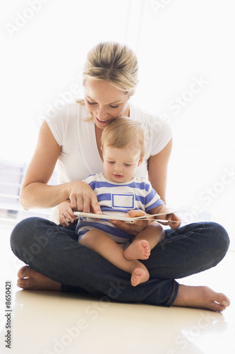 Mother and baby indoors reading book and smiling