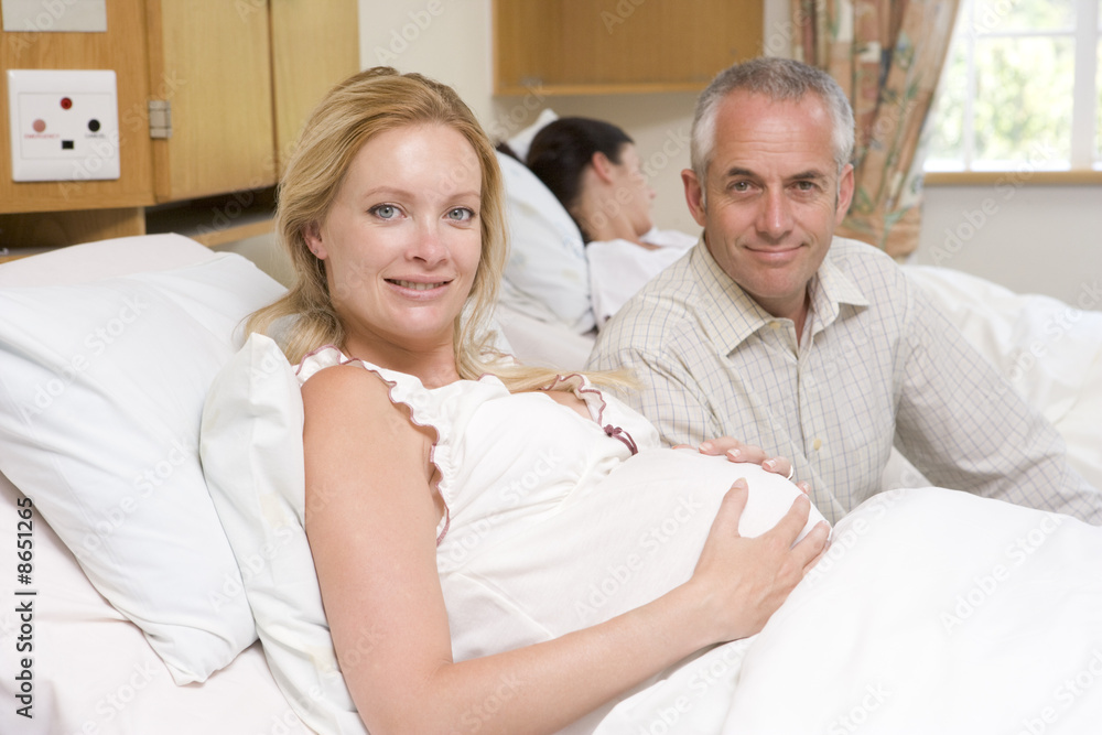 Pregnant woman with husband in hospital smiling Pregnant woman with husband in hospital smiling