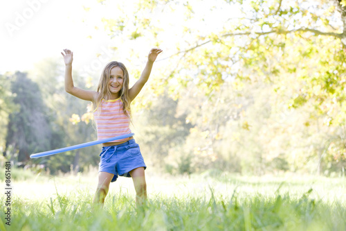 Young girl with hula hoop outdoors smiling photo