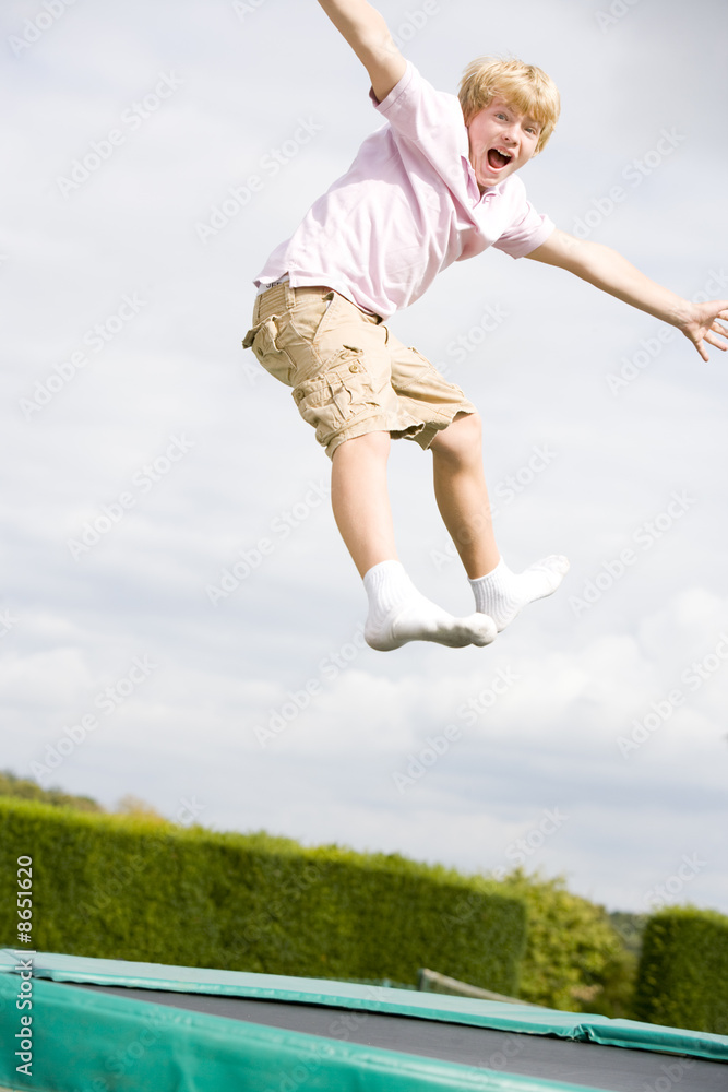 Young boy jumping on trampoline smiling Young boy jumping on trampoline smiling