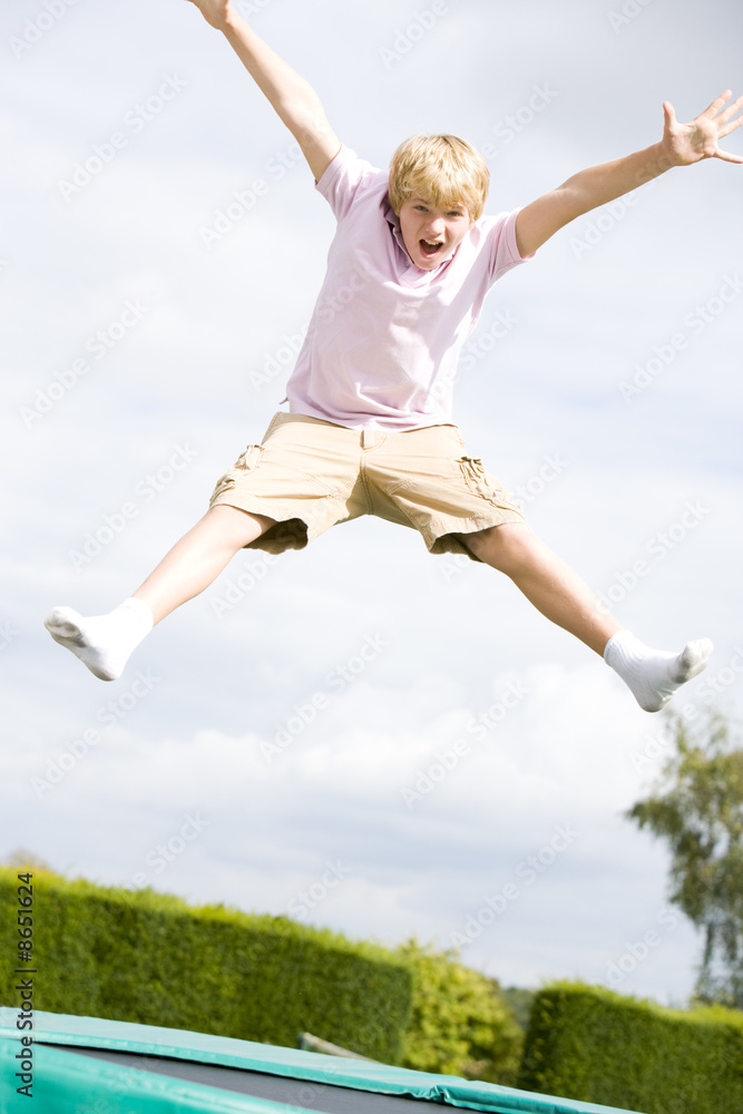 Young boy jumping on trampoline smiling Young boy jumping on trampoline smiling